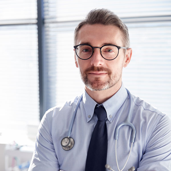 Portrait of smiling mature male doctor with stetho J2MWQDT